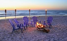 Beach chairs around a bonfire at sunset